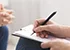 Therapist writing notes during rehab session with patient